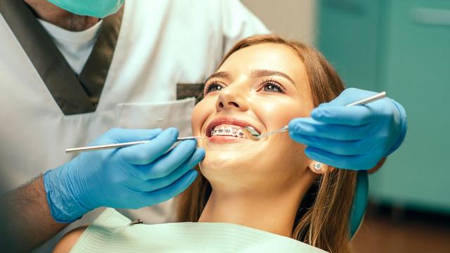 Orthodontist inspecting a patient’s metal braces.
