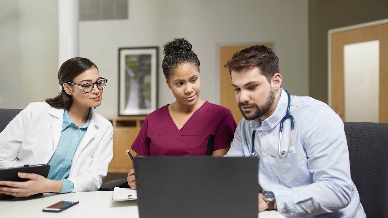 Medical care team consulting at table with computer 