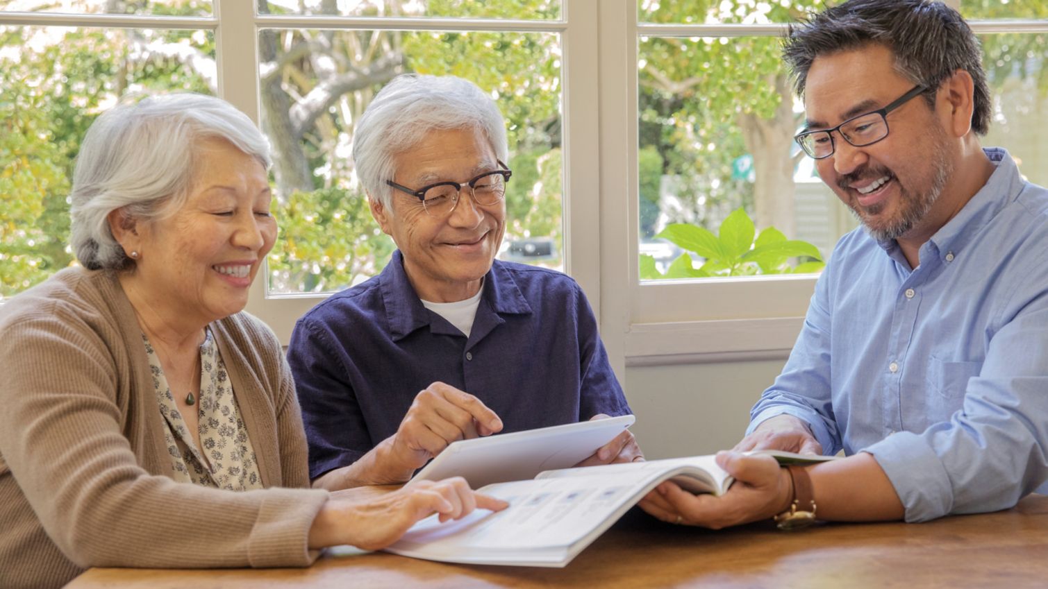 A couple sits at a table and reads a booklet with their agent. 