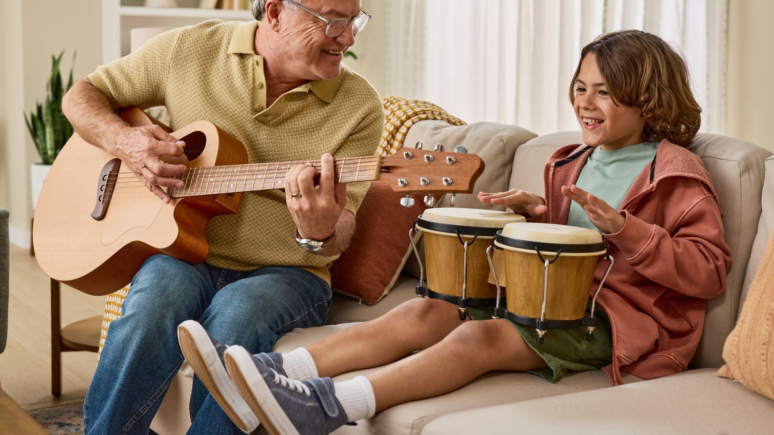 Smiling man playing music with grandson.