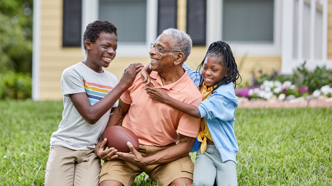 Older man playing in yard with two younger children