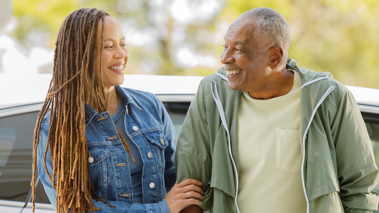 African American man using a walker is assisted by younger African American woman.
