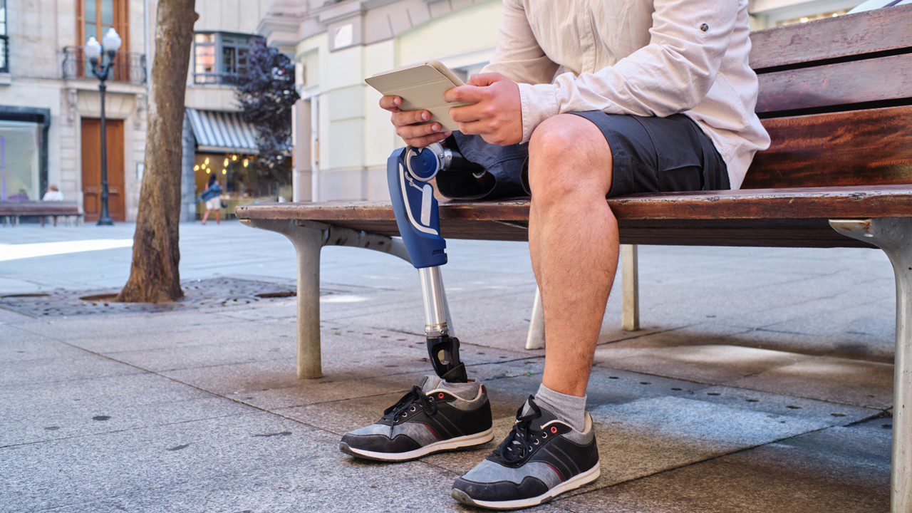 Man with robotic prosthetic leg sitting on bench