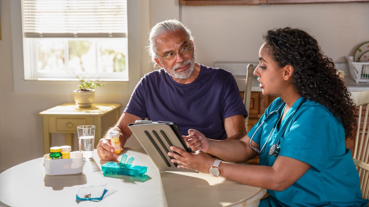 Older man discussing medication with a home nurse