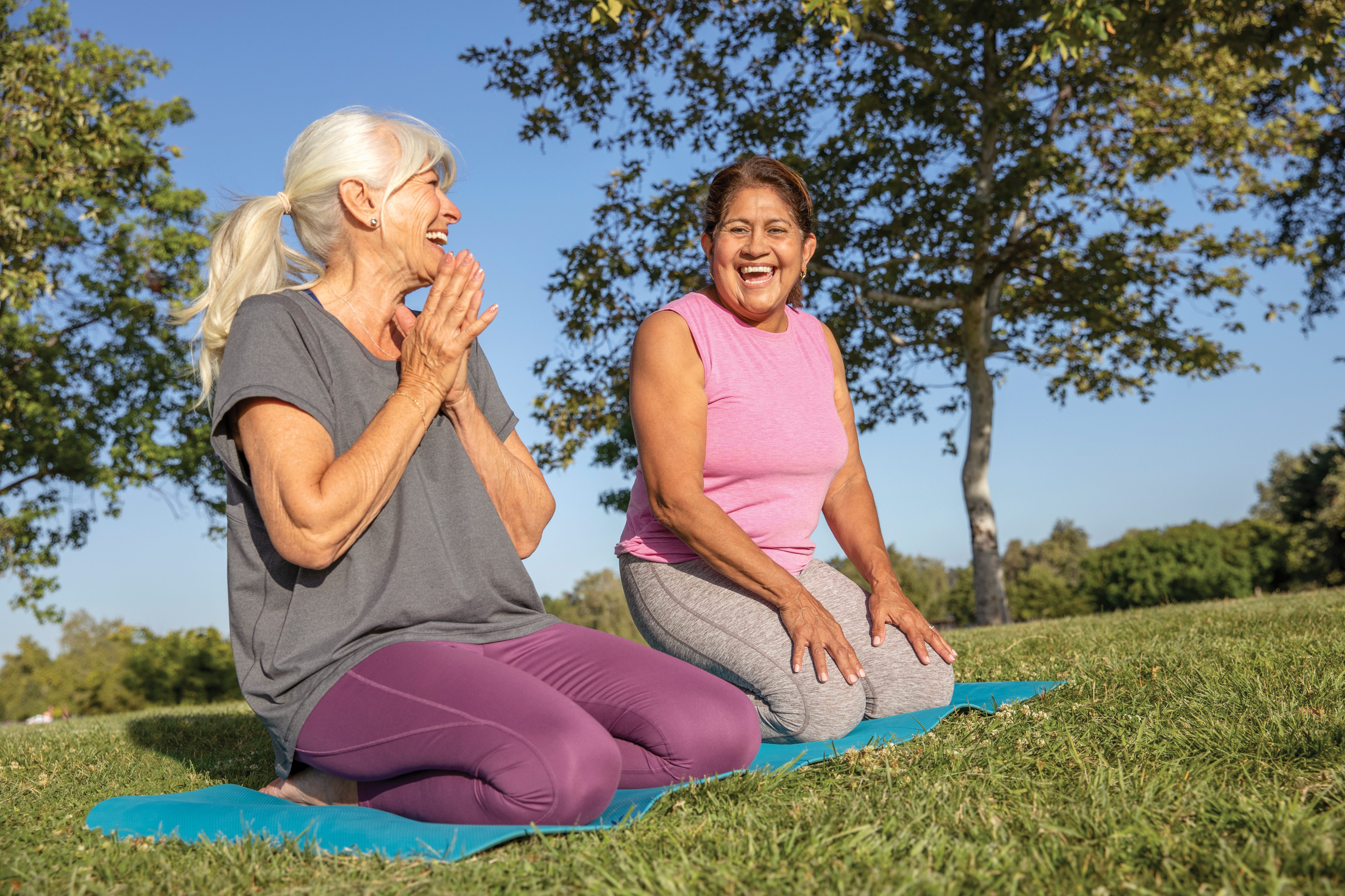Senior women outside at a park stretching on a yoga mat