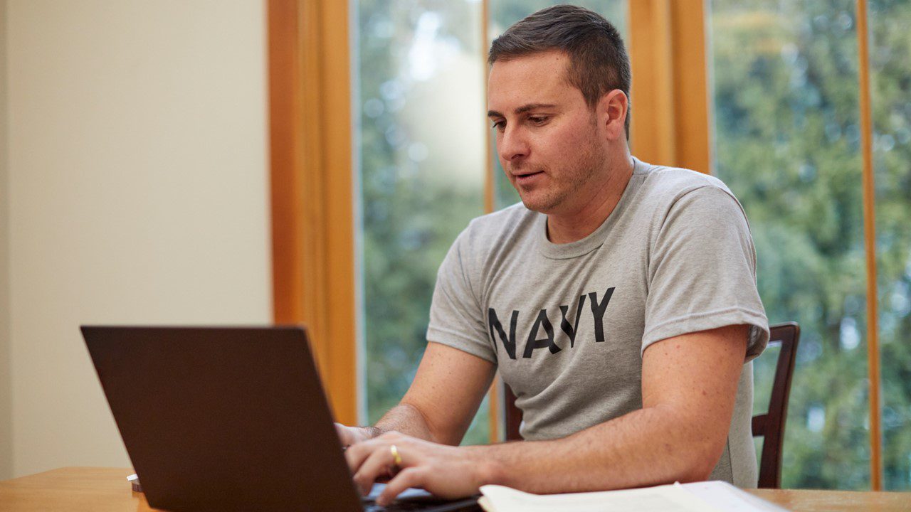 Man who may be Navy veteran working at a computer