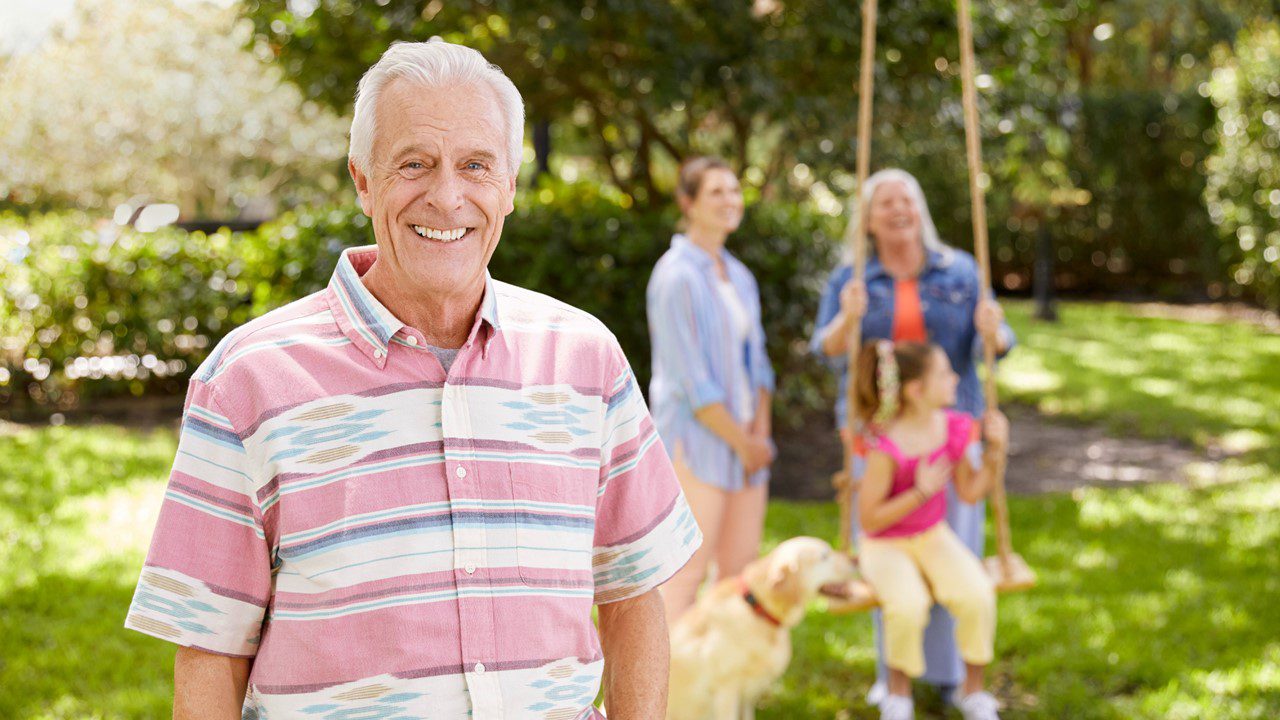 Older man smiling in backyard with family