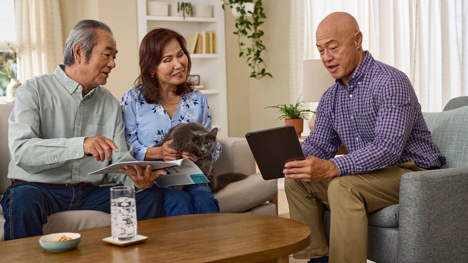 A couple sits at a table and reads a booklet with their agent. 