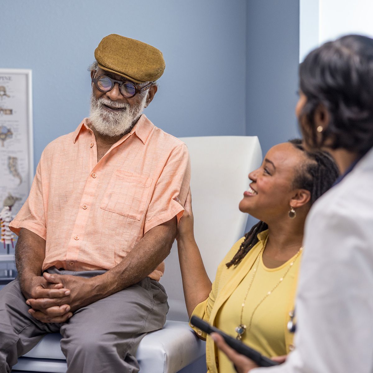 Senior patient and caregiver talking with his doctor​​ 