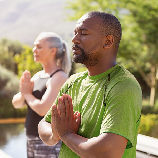 A older couple standing in a meditation pose