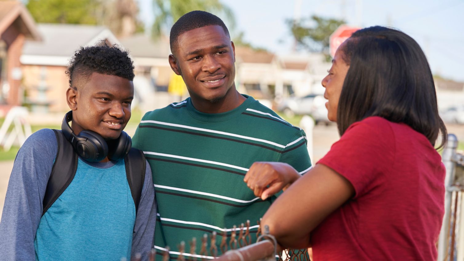 Adult talking to young people over a fence.