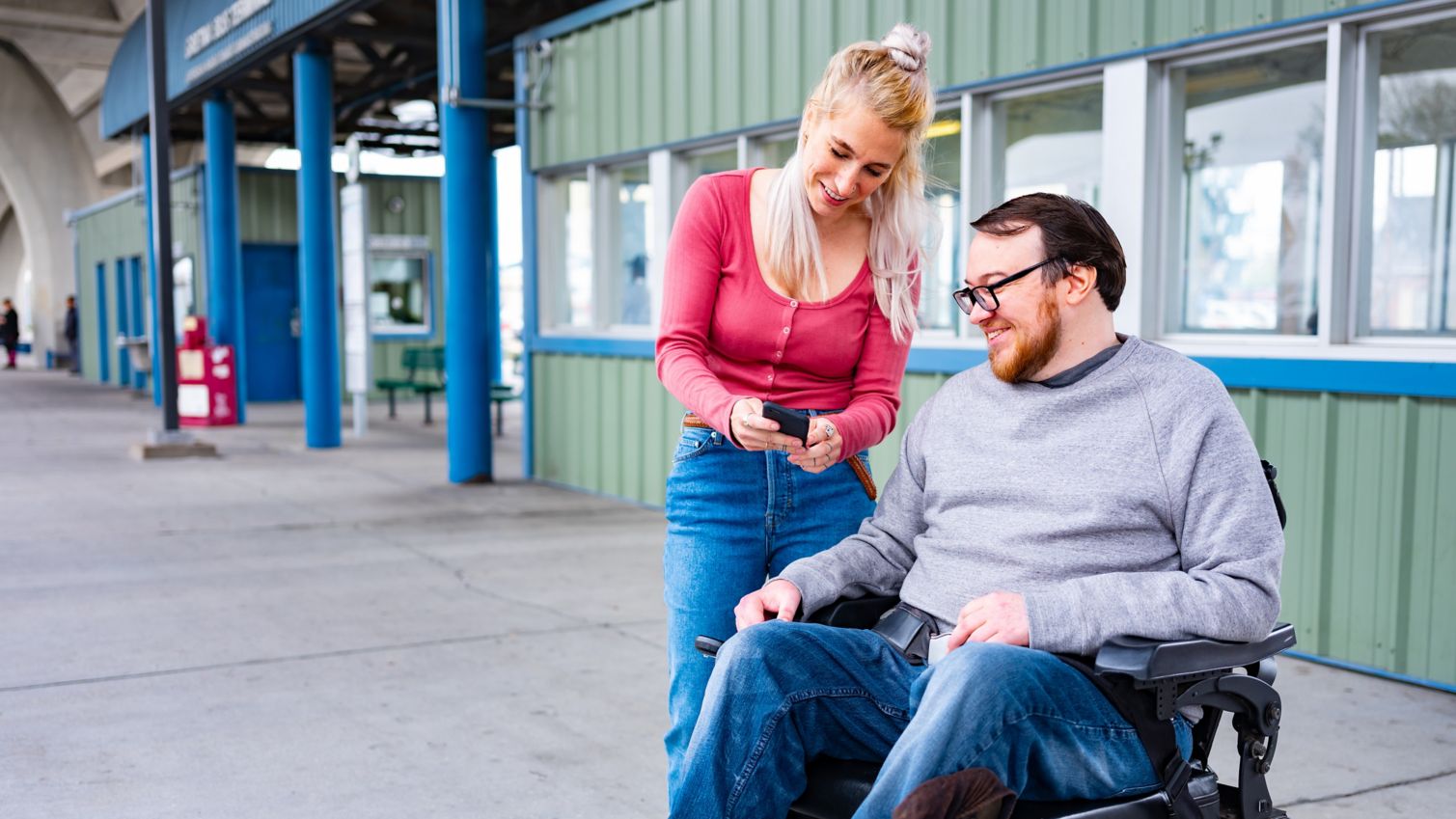 Blind man and caregiver look at the cellphone at bus