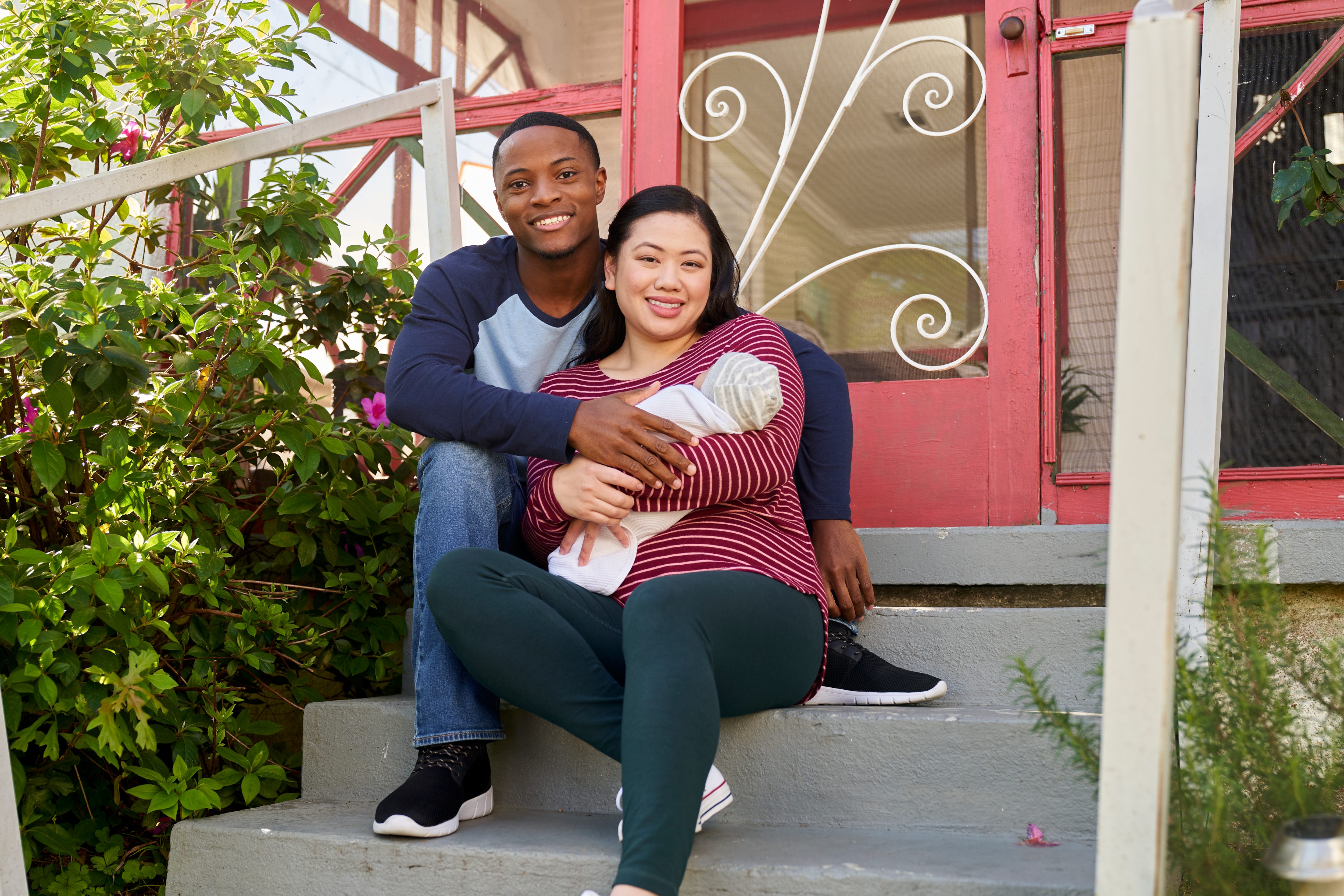 Young couple with baby sitting on front steps to home