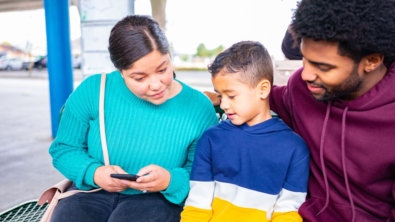 Parents talk to young son outside on bench