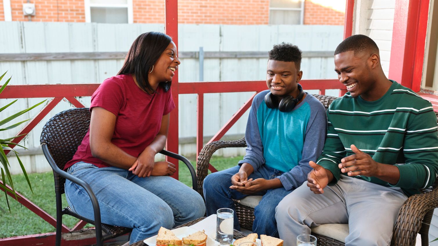 Family sits on outside porch enjoying food