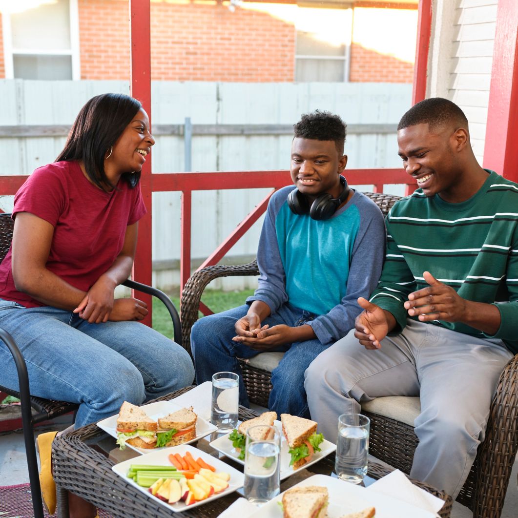 Family sits on outside porch enjoying food
