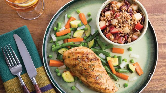 Meal of chicken, vegatables and fruit on table.