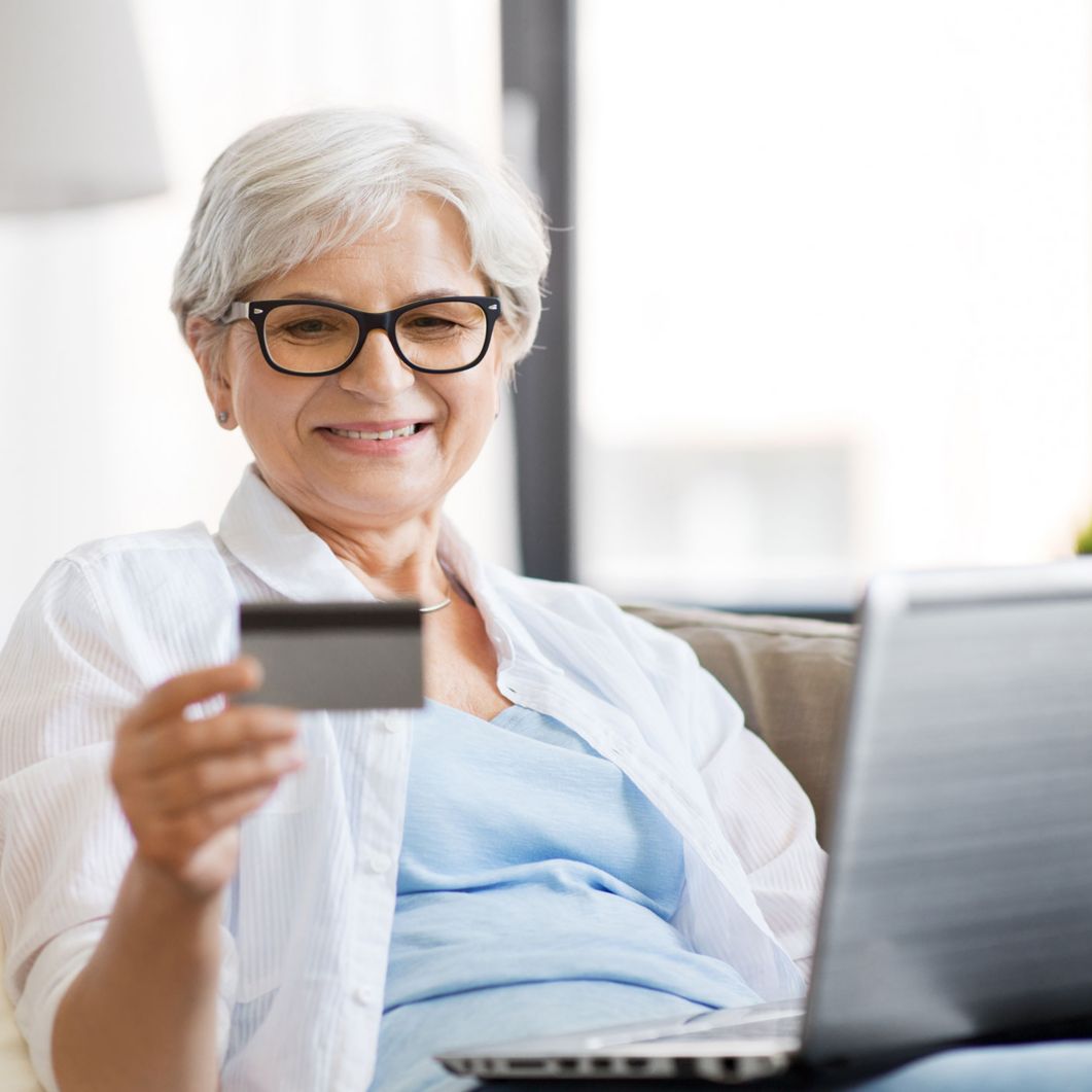 Older woman with laptop using credit card.