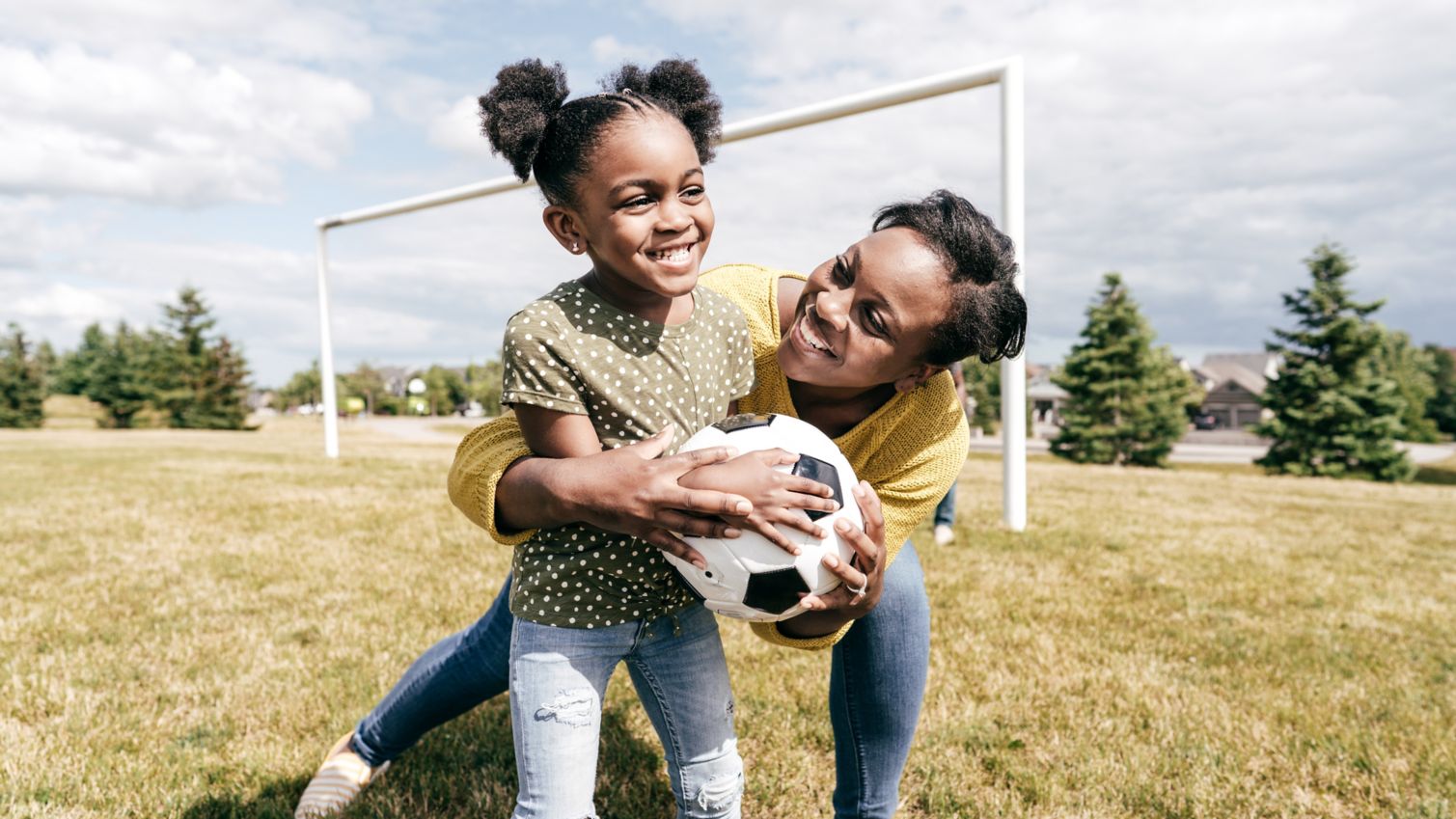 Mom and daughter play soccer outside