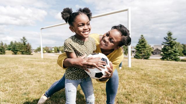 Mom and daughter play soccer outside