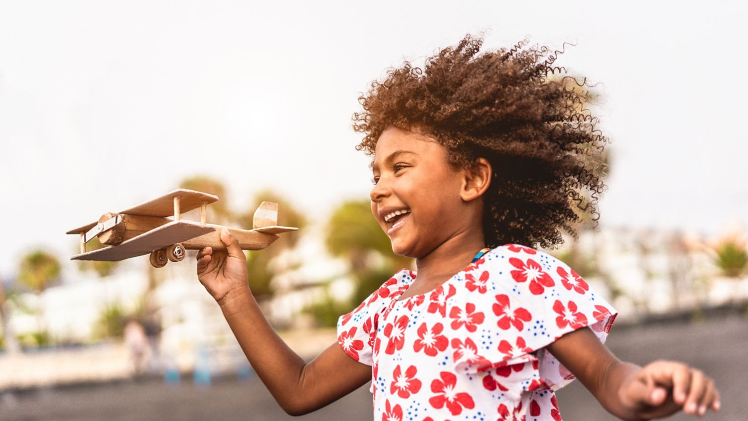 Young girl plays outside with a toy airplane