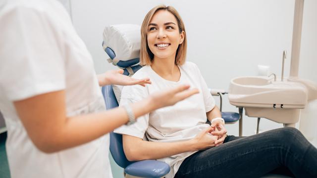 A woman smiles as she speaks with her dentist. 