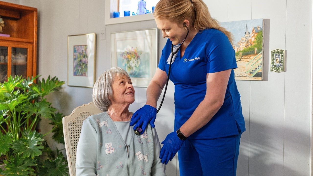 Home care nurse taking vitals of older female patient with gray hair