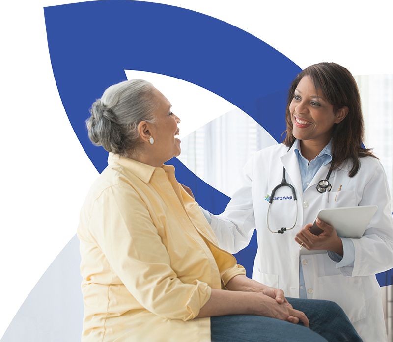 Female doctor talking to seated patient in front of CenterWell logo