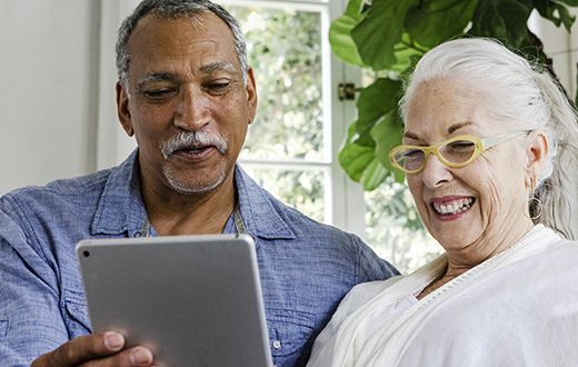 Elderly man and woman looking at iPad tablet together exploring the CenterWell health portal