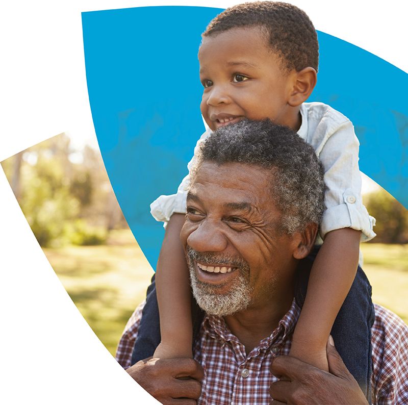 Elderly man carrying his grandchild on his shoulders in front of the CenterWell logo