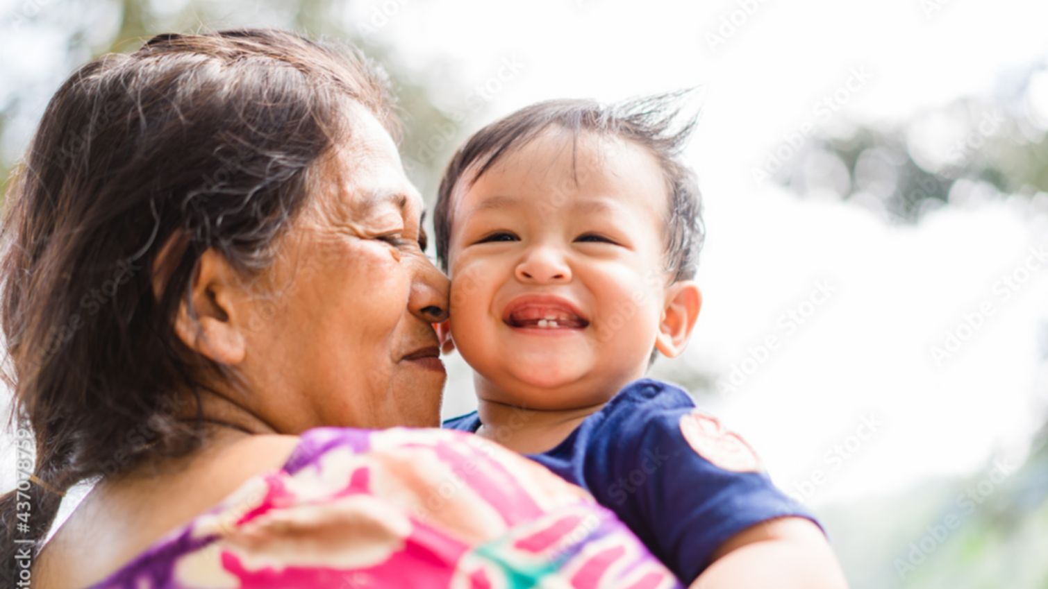 Native American woman holds a young boy in her arms and smiles