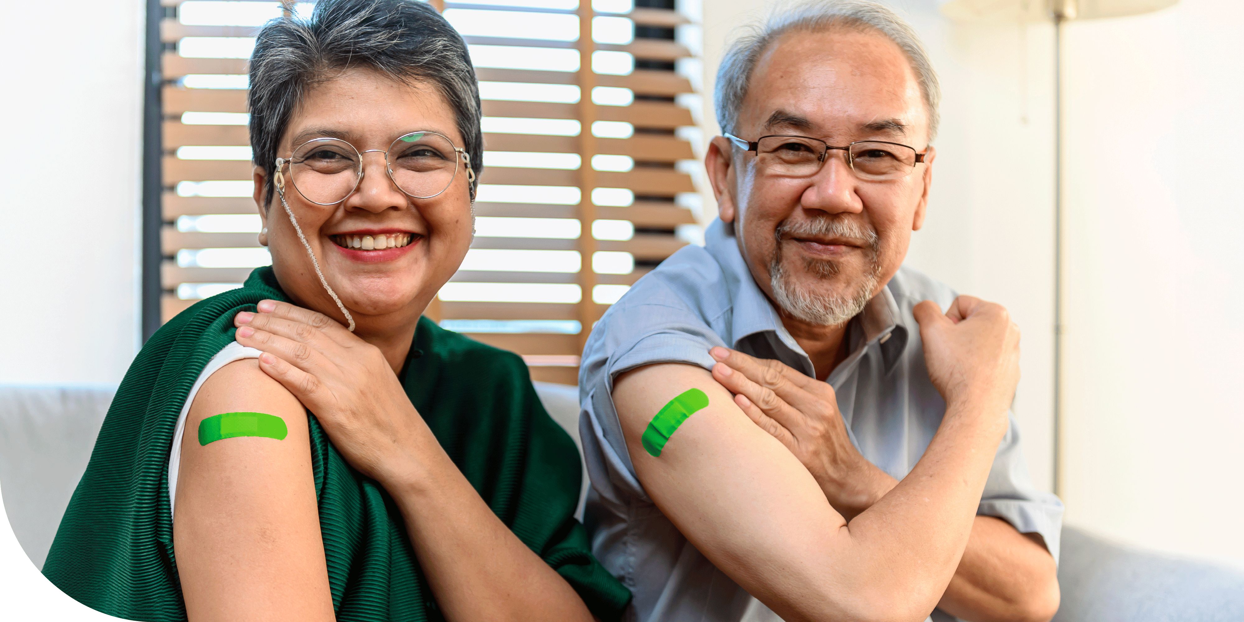 Smiling senior couple showing their arms with colorful bandages after receiving their flu vaccinations