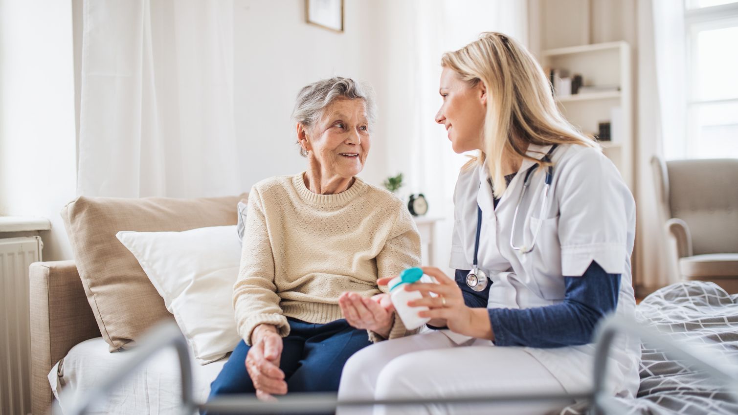 A healthcare professionial talks to an elderly patient on her bedside