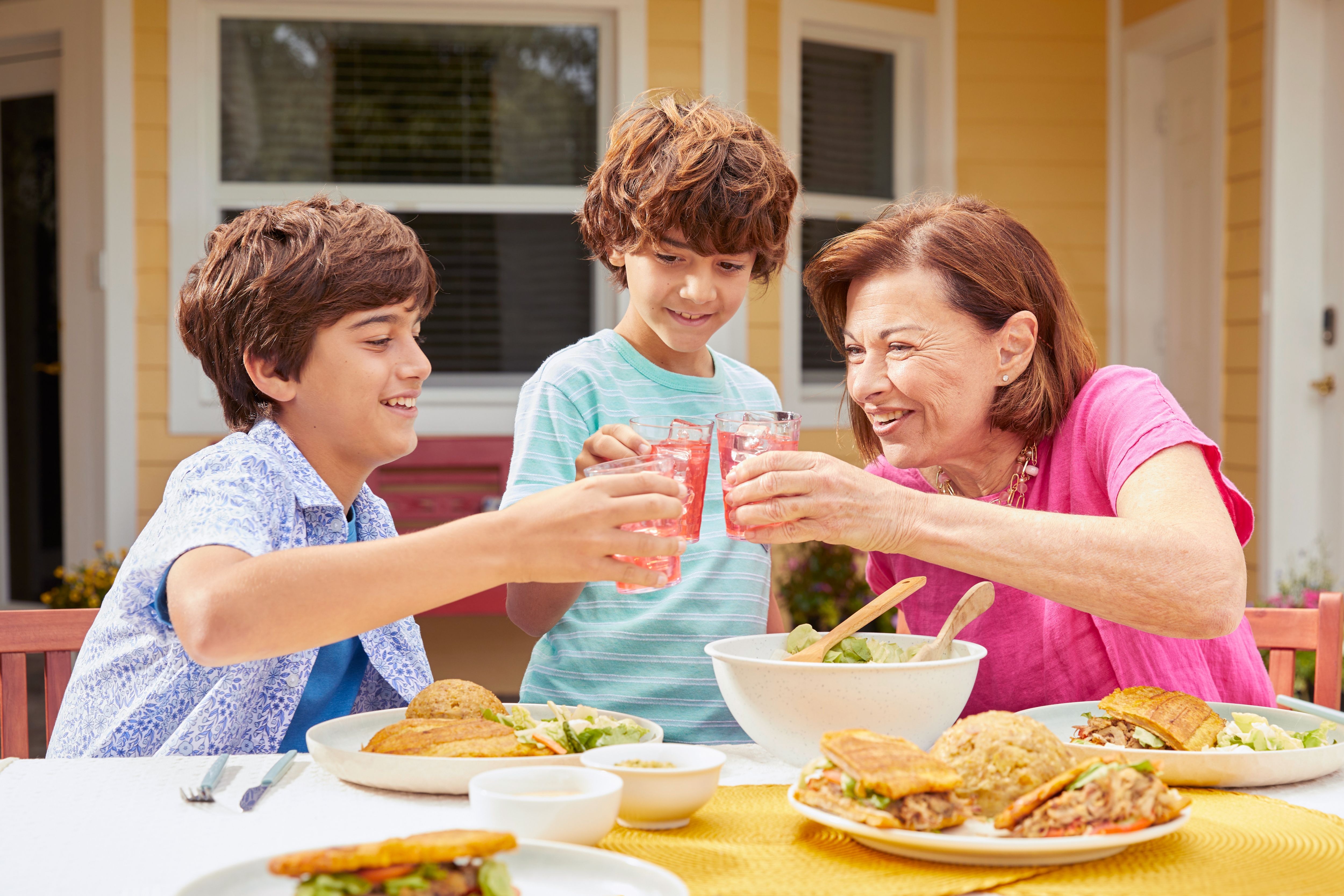 Senior woman enjoying an outdoor meal with her two grandsons